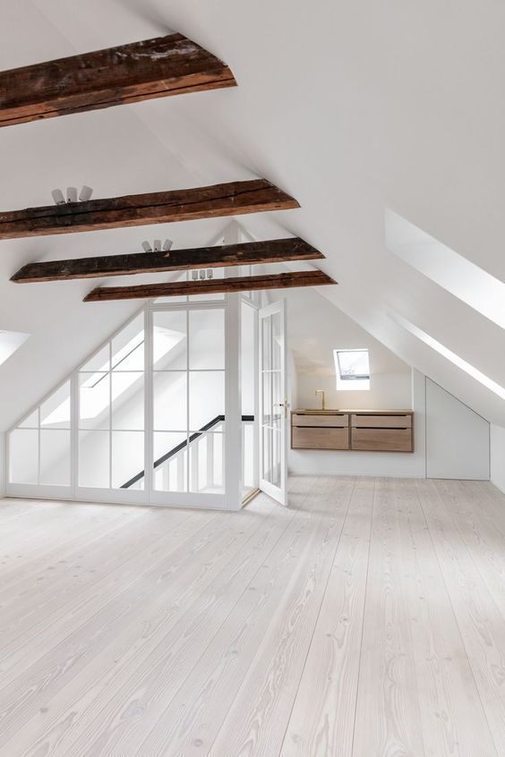 an empty room with wooden floors and white walls, in the middle of a loft