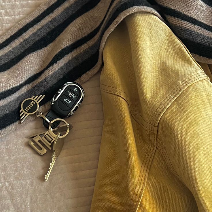 a pair of keys laying on top of a bed next to a jacket and scarf