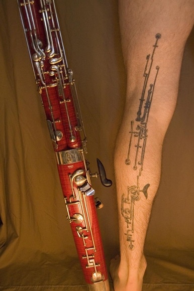 a person's leg with a tattoo on it and a red instrument in the foreground