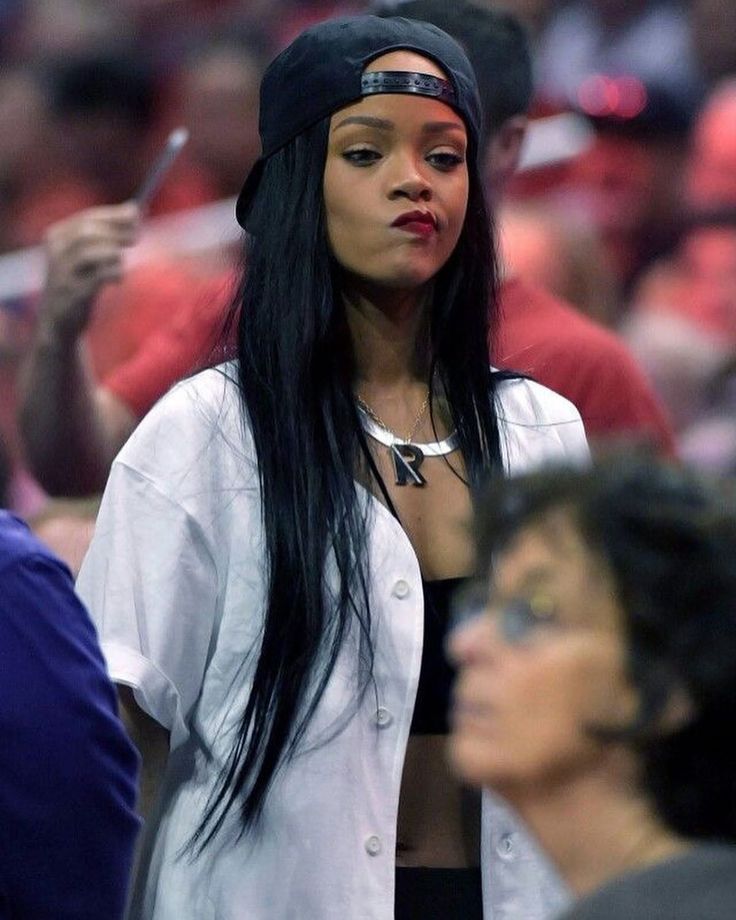 a woman with long black hair standing in front of a crowd at a basketball game