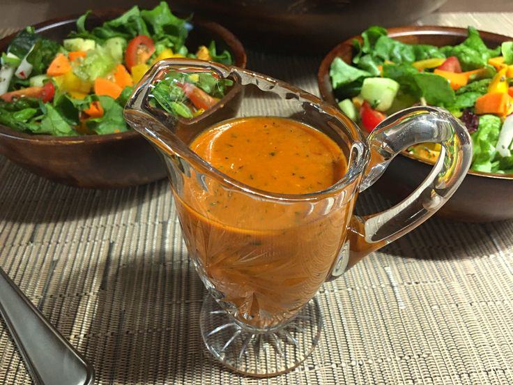 a glass pitcher filled with liquid next to bowls of salad