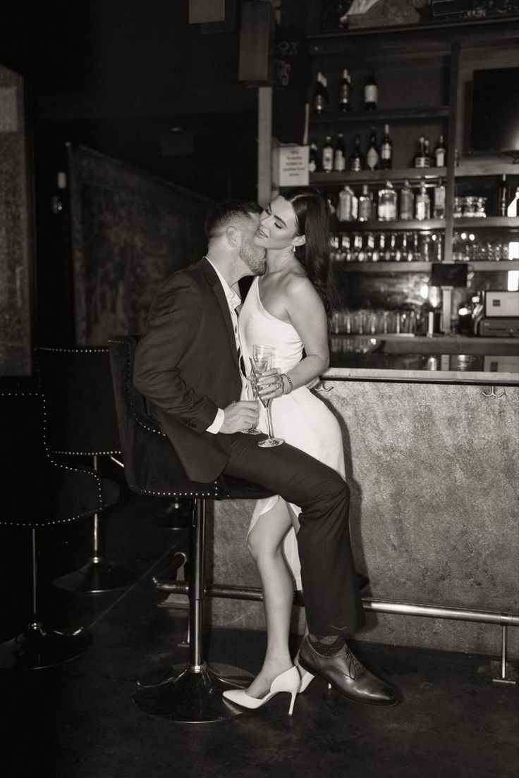 a man and woman kissing in front of a bar