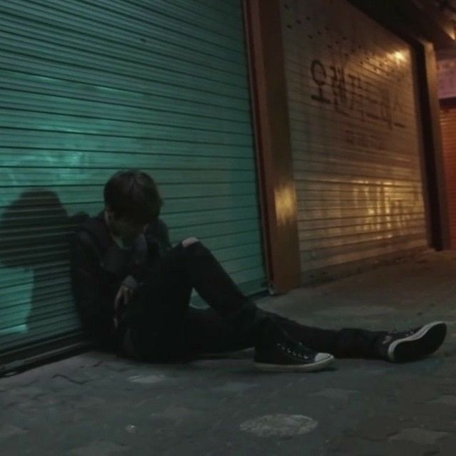 a man sitting on the ground in front of a garage door