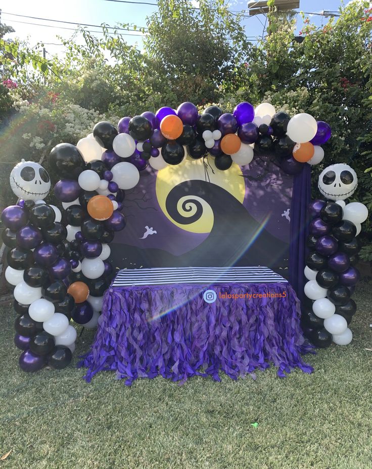 the balloon arch is decorated with purple and orange balloons, black and white decorations, and a jack - o - lantern sign