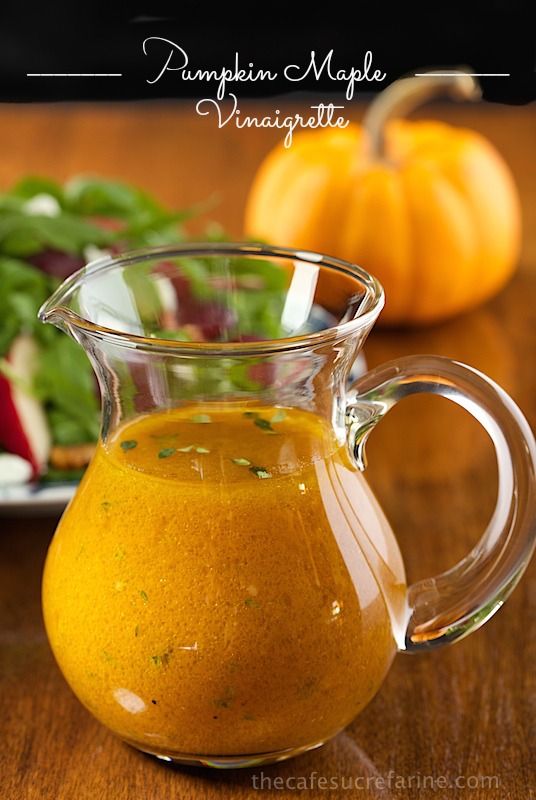 a glass pitcher filled with liquid sitting on top of a wooden table next to vegetables