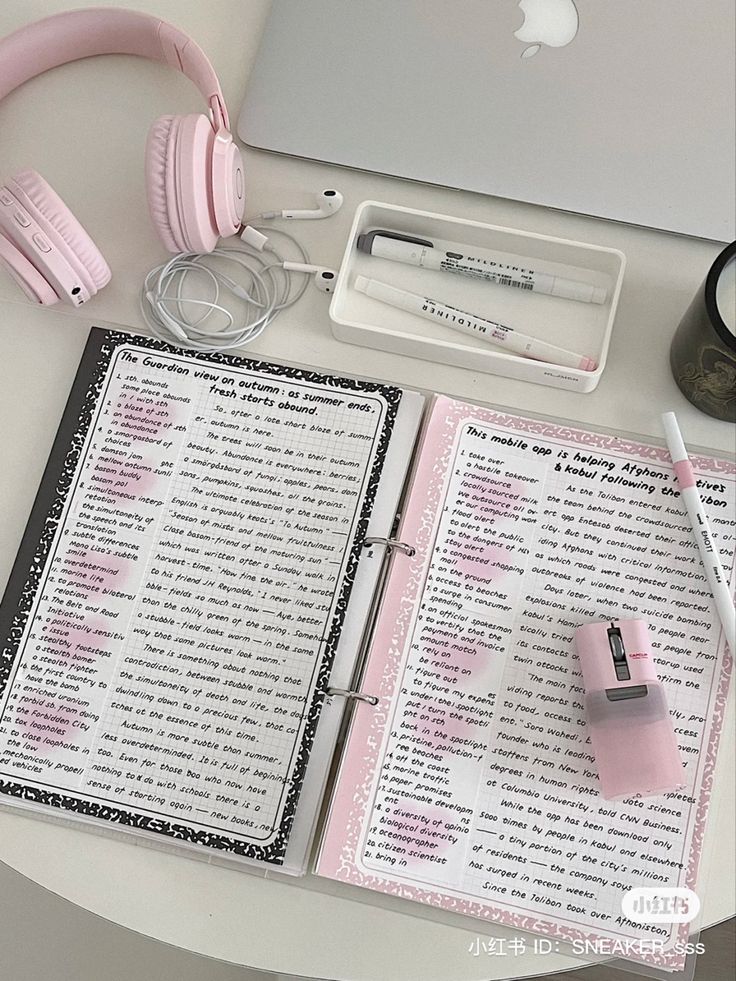 an open notebook sitting on top of a table next to headphones and a laptop