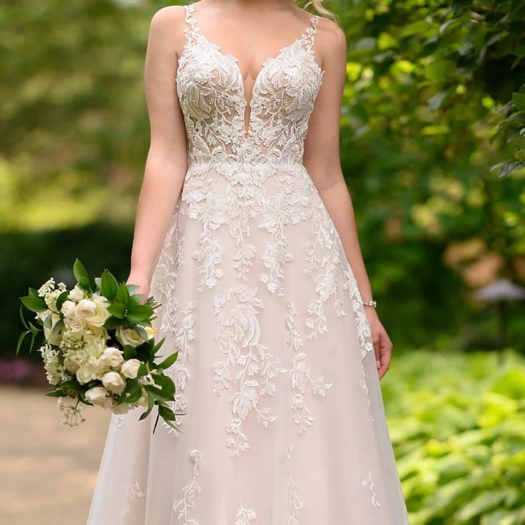 a woman in a wedding dress holding a bouquet and looking at the camera while standing outside