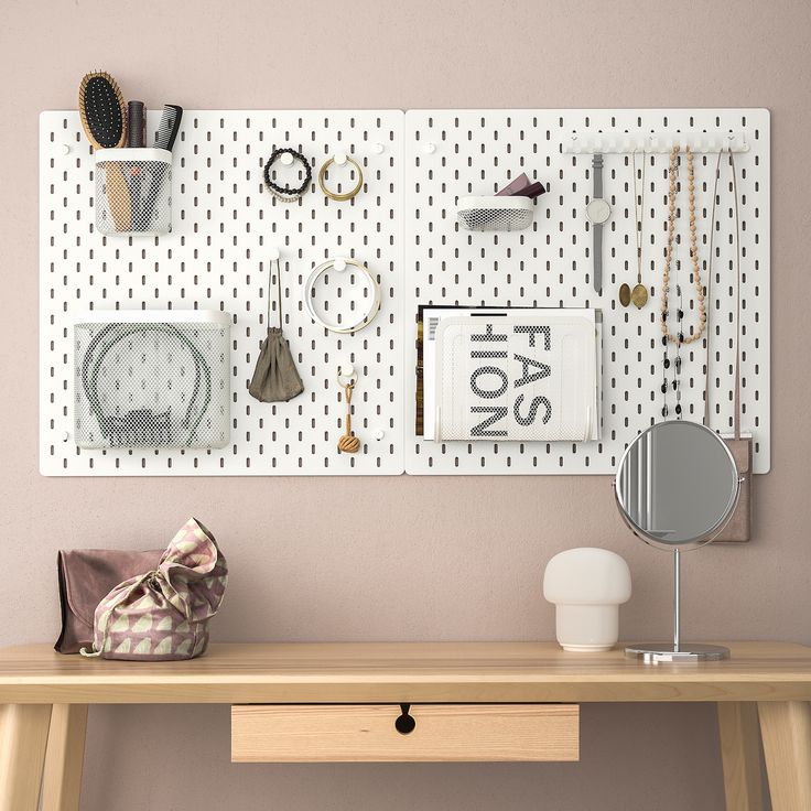 a wooden desk topped with a mirror next to a wall covered in jewelry and accessories