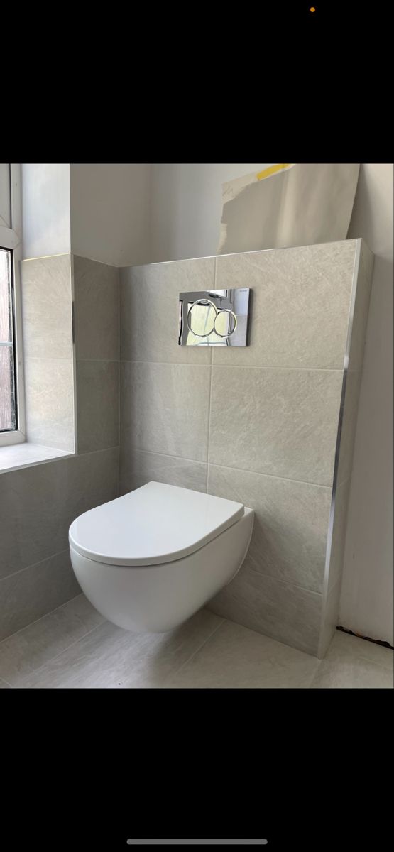 a white toilet sitting next to a window in a bathroom