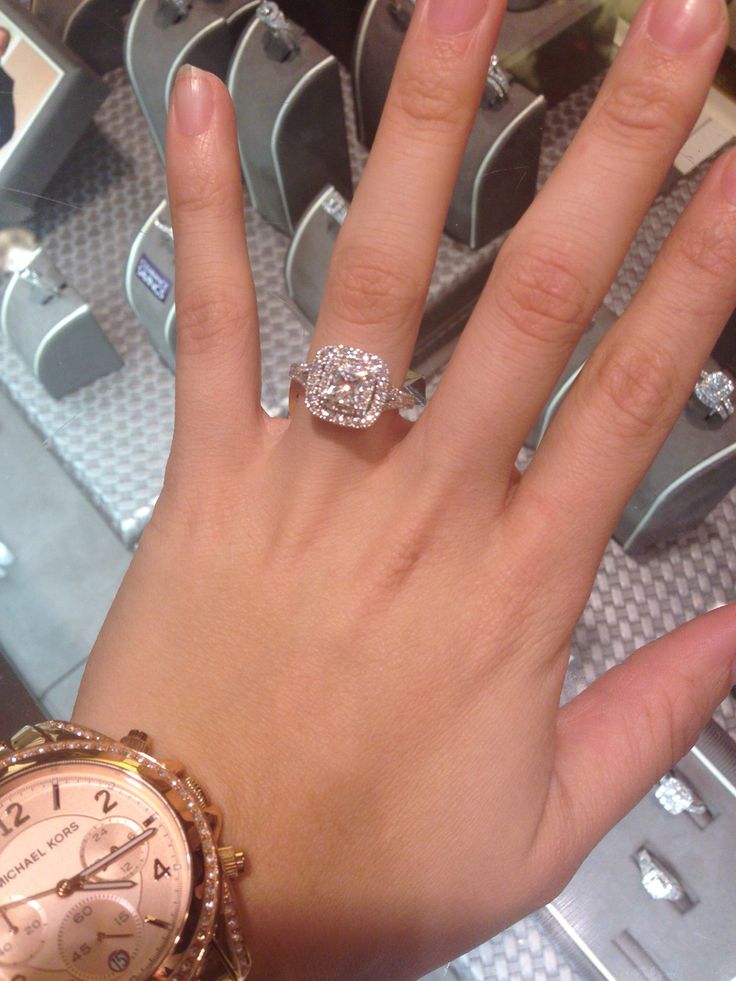 a woman's hand with a diamond ring on top of her wrist next to a watch