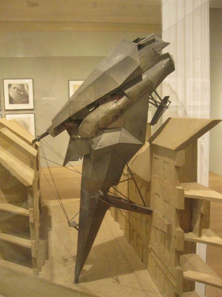 a model of a fighter jet on display in a glass case with stairs and pictures behind it