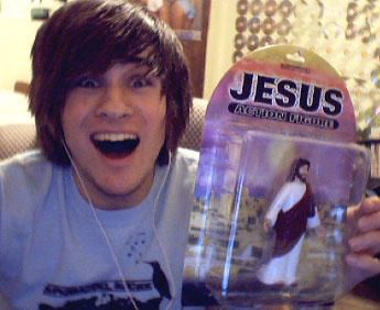 a young man holding up a plastic jesus figure in front of his face with headphones on