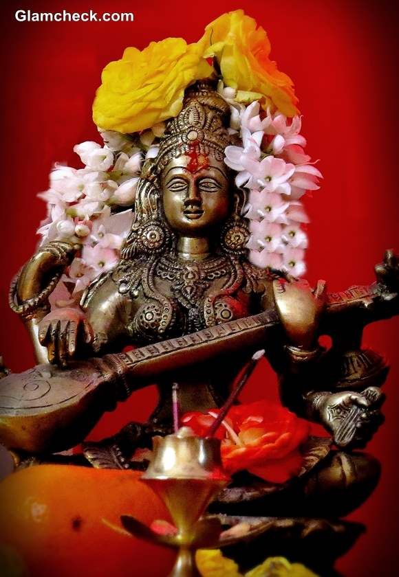 a statue with flowers on its head and an instrument in the foreground, against a red background