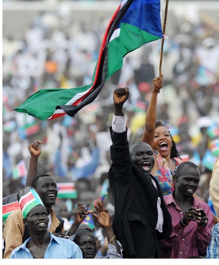 a group of people holding flags and standing next to each other in front of a crowd