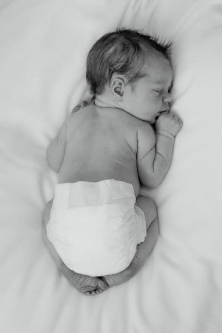 a black and white photo of a baby wrapped in a diaper