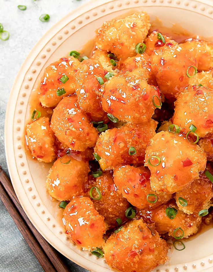 a white plate topped with fried food next to chopsticks