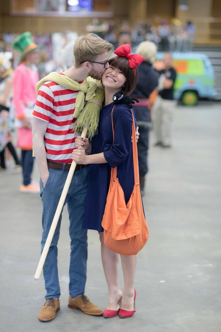 a man and woman standing next to each other in front of a building with lots of people