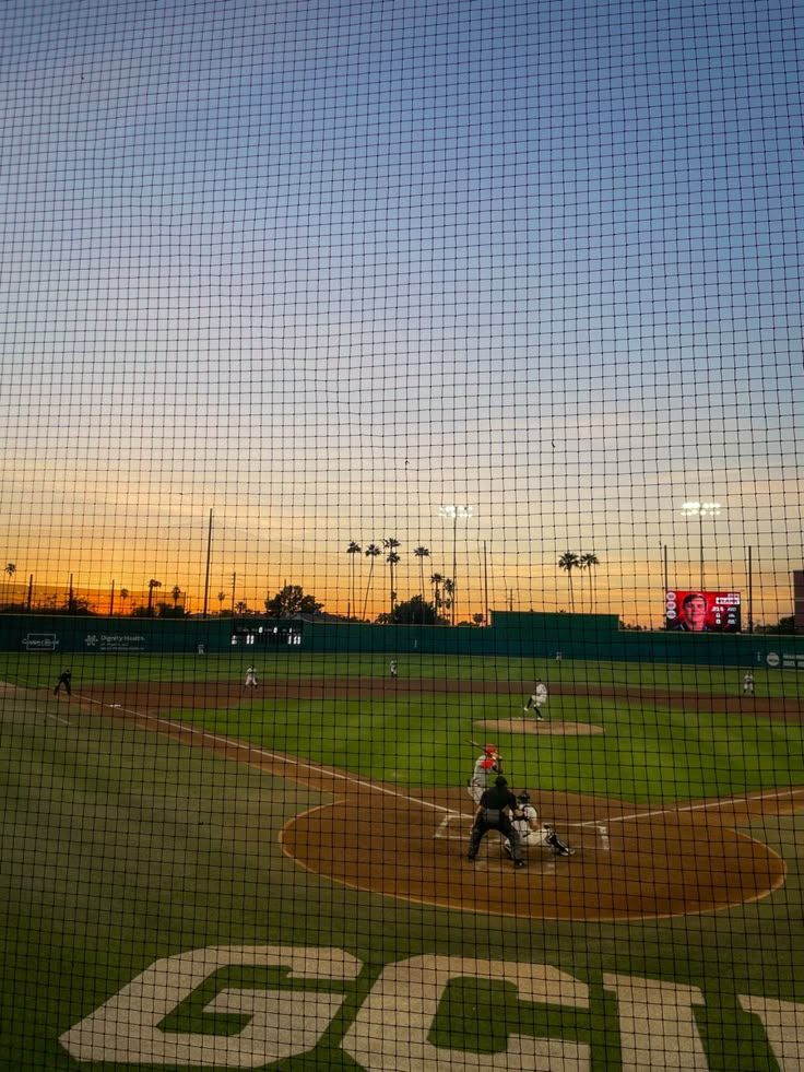 a baseball game in progress with the sun setting