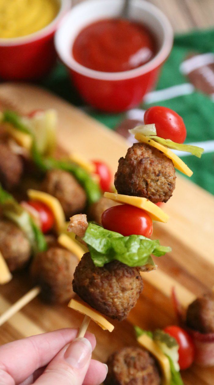 a person is holding a skewer with meatballs and vegetables on it, ready to be served