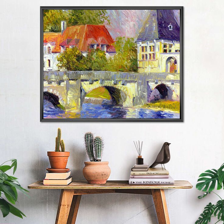 a painting hanging on the wall above a table with potted plants in front of it