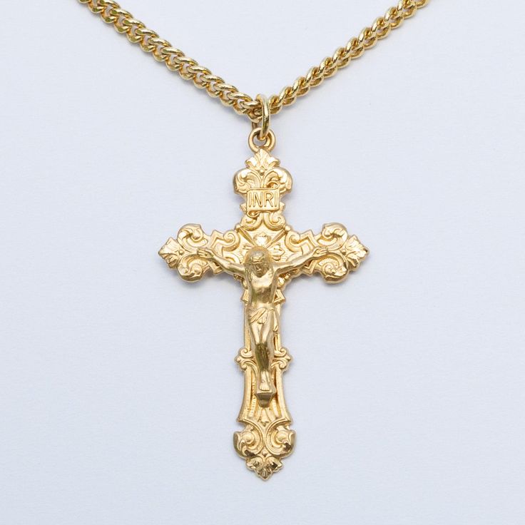 a gold cross is shown on a white surface with a chain attached to the cross