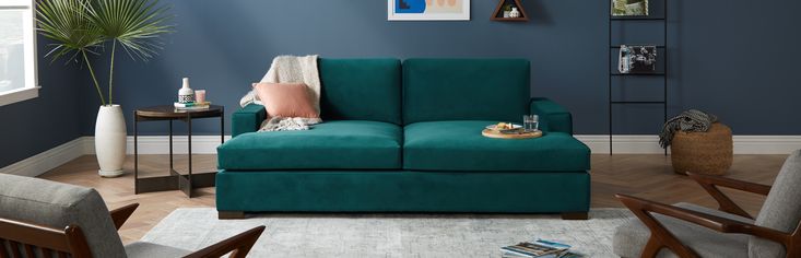 a living room with blue walls and wooden furniture in the corner, including a green couch