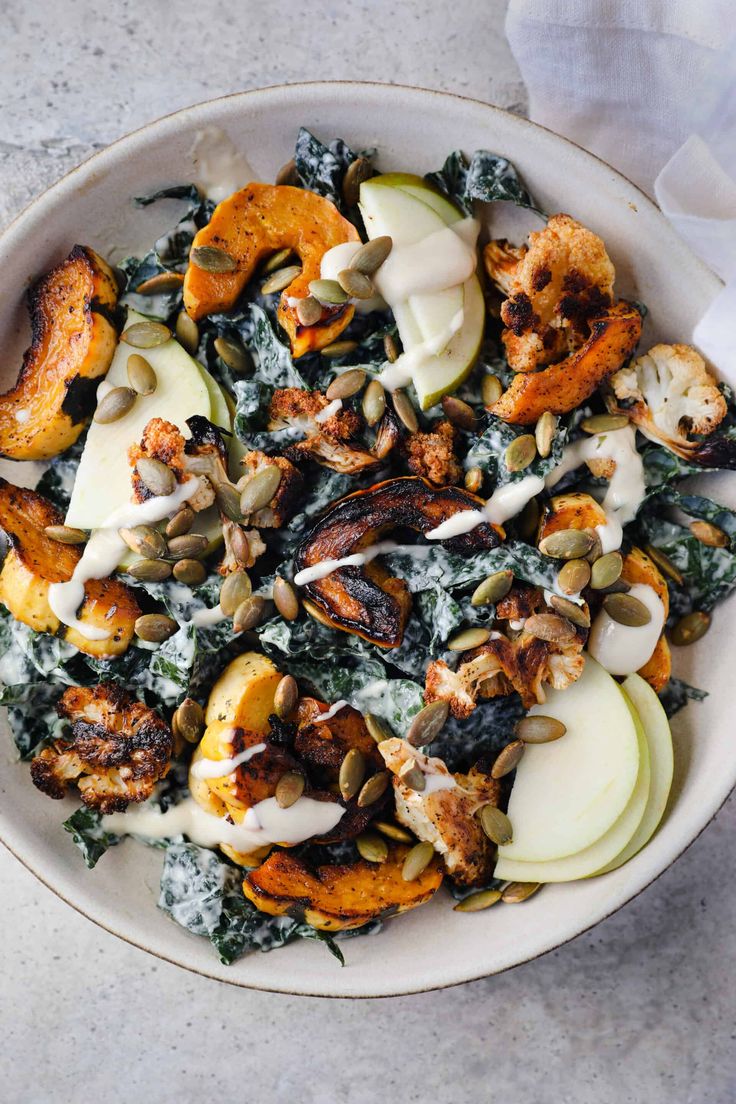 a white bowl filled with lots of food on top of a marble countertop next to napkins