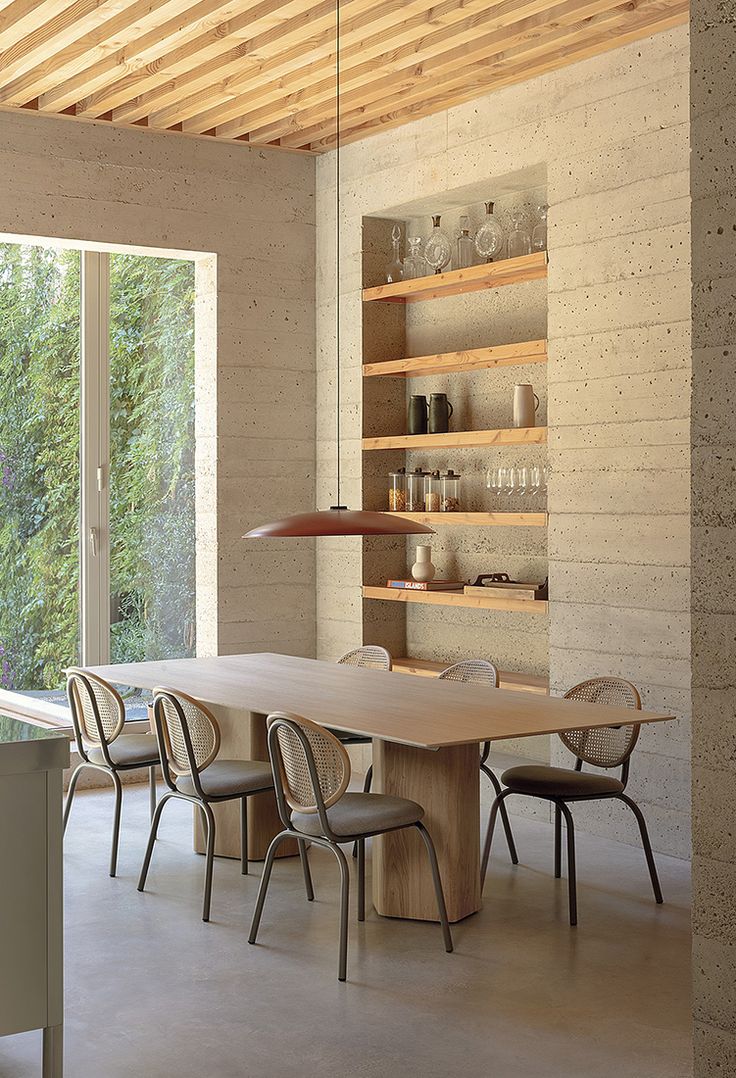 a table and chairs in a room next to a wall with open shelves on it