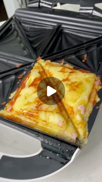 a panini being cooked on top of an electric griddle oven with the lid open