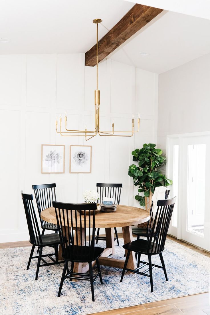 a dinning room table with chairs and a potted plant in the center is surrounded by white paneling