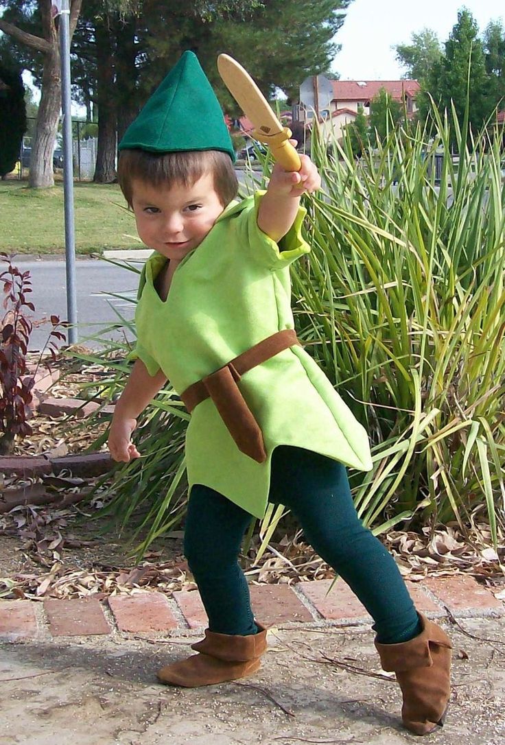 a young boy dressed as peter the neverlander holding a stick and wearing a green hat