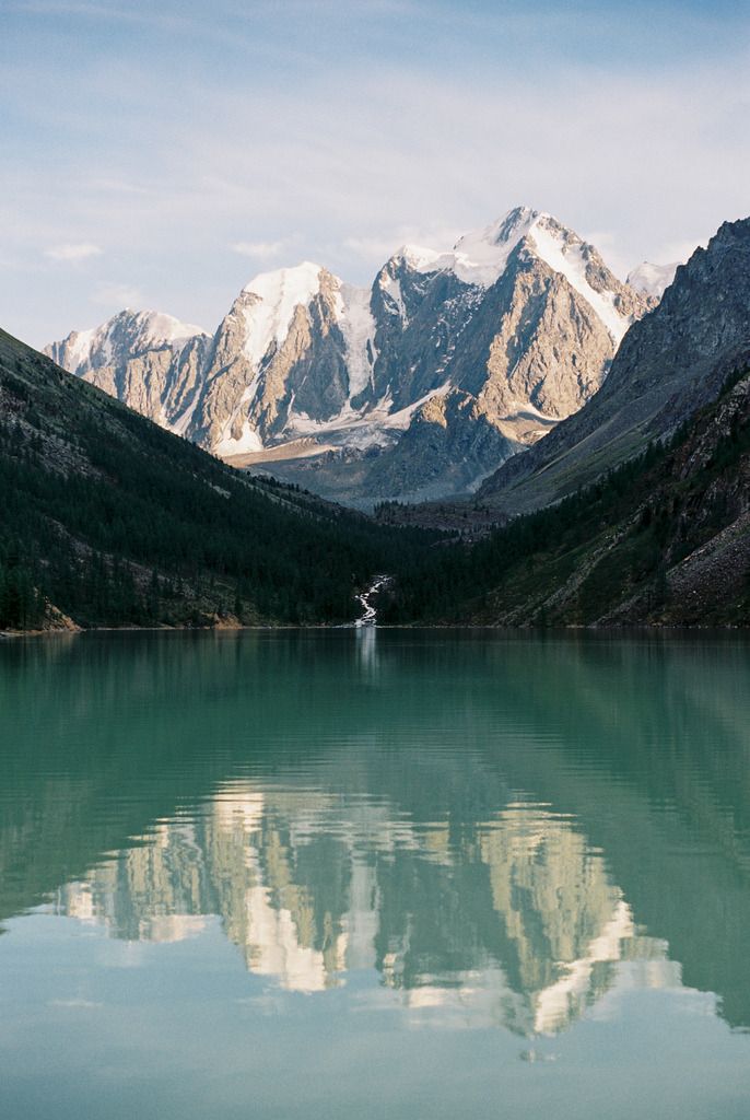 the mountains are reflected in the still water