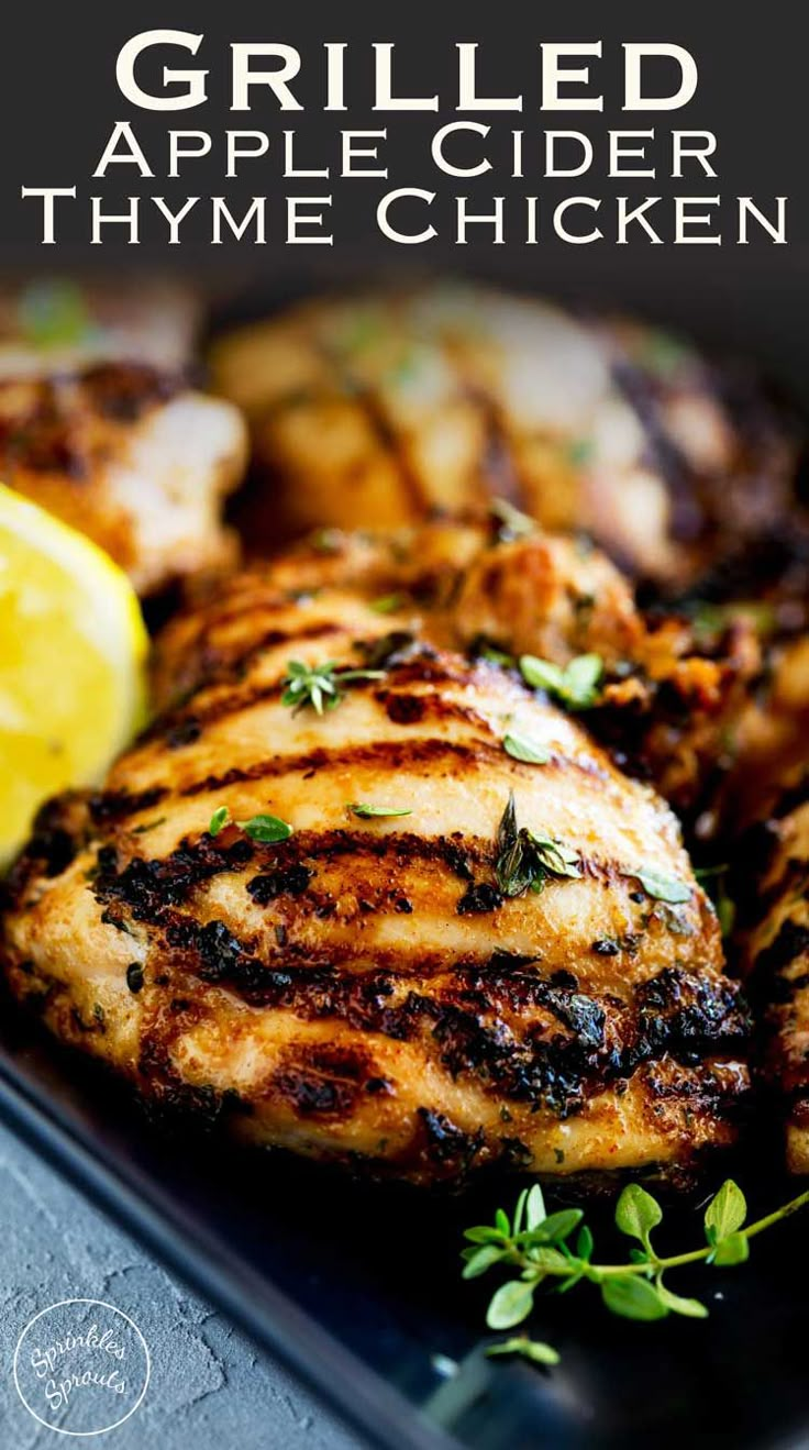 grilled apple cider thyme chicken on a black plate with lemon wedges