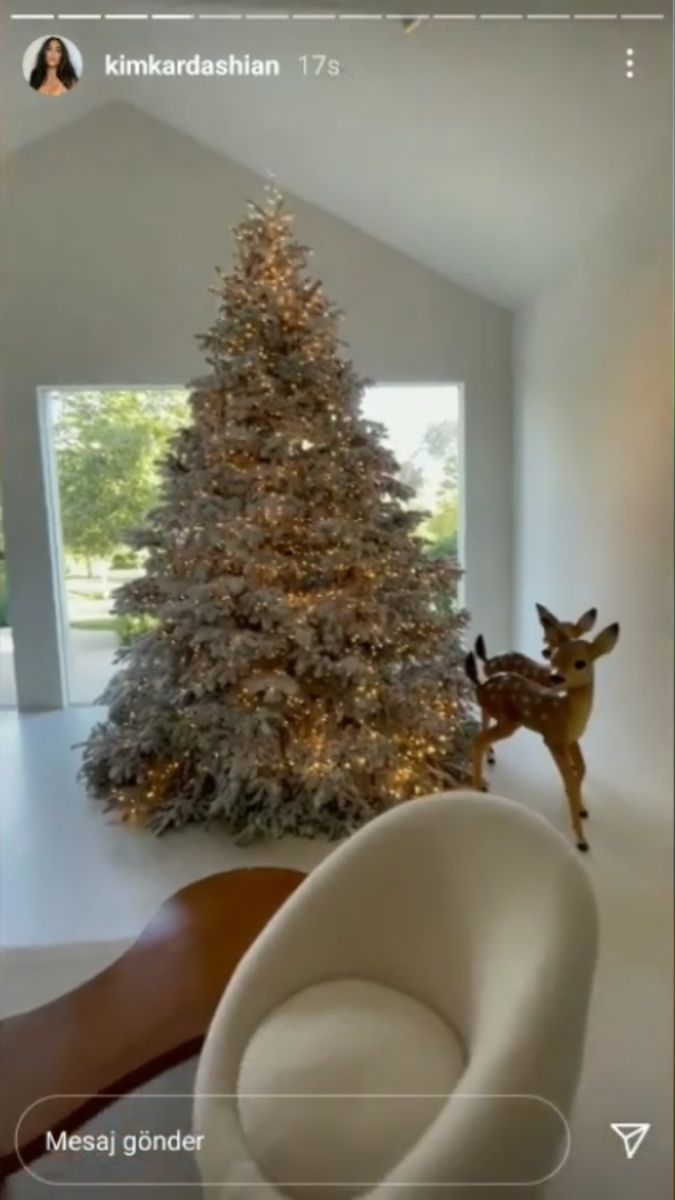 a living room with a christmas tree in the corner and a white chair next to it