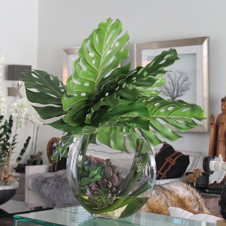 a glass table topped with a vase filled with plants