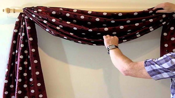 a man holding up a red and white polka dot curtain