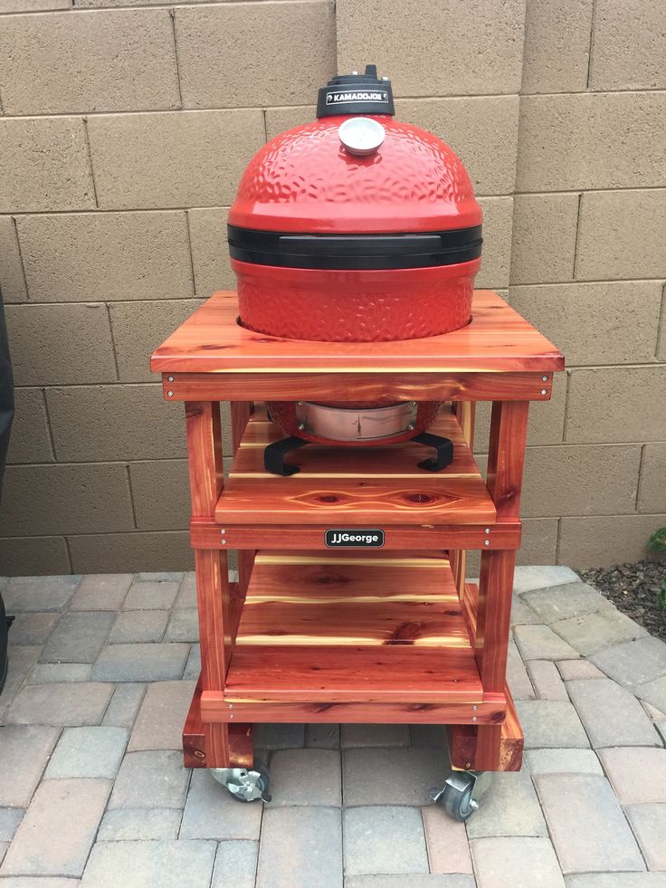 a big red grill sitting on top of a wooden stand