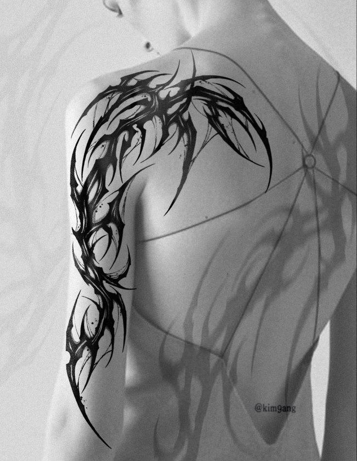 the back of a woman's shoulder and arm with black ink art work on it