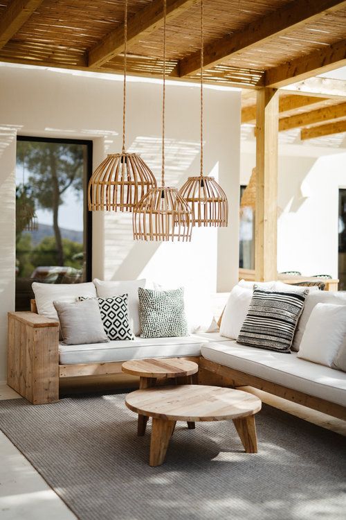 a living room with white couches and wooden tables in front of a large window