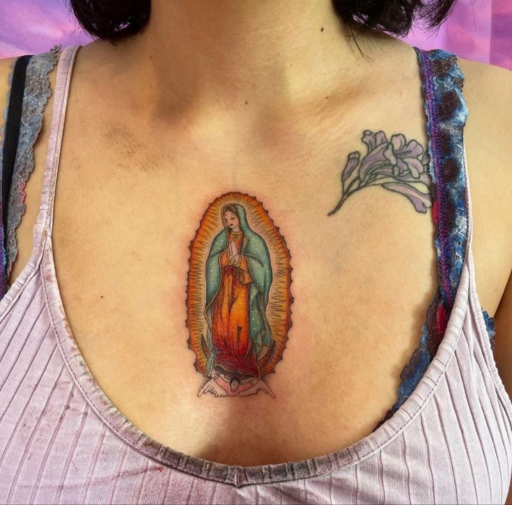 a woman with a tattoo on her chest has the image of mary and child jesus