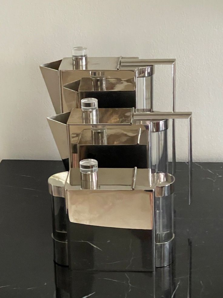 three silver vases sitting on top of a black table