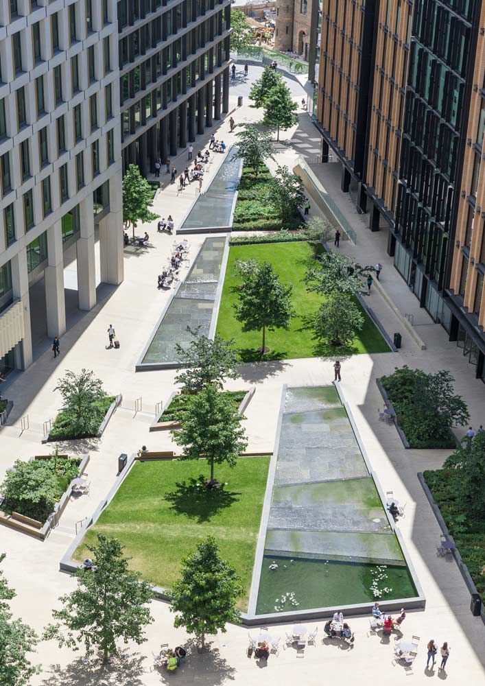 an aerial view of people walking and sitting on benches in the middle of a park