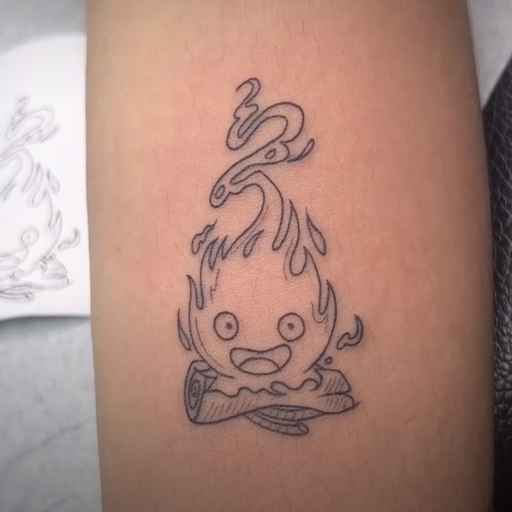 a small tattoo on the leg of a woman with a dragon head and flames in it