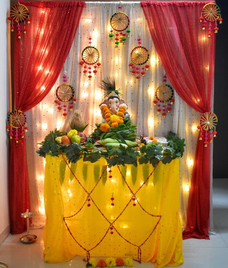 a table topped with fruit and vegetables on top of a white floor next to a red curtain