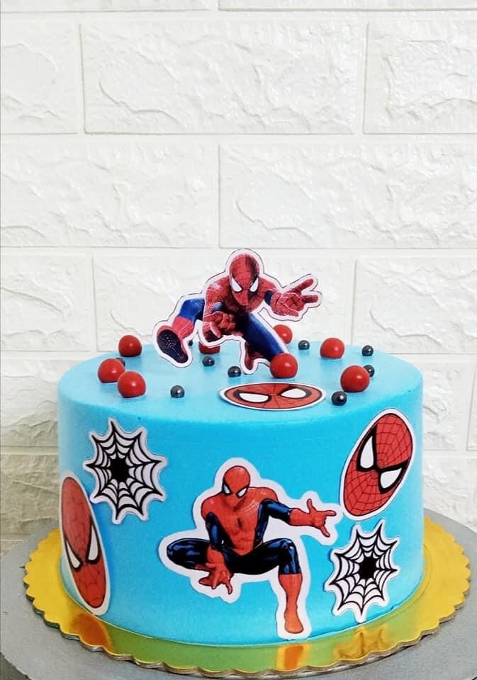 a spiderman themed birthday cake with decorations on the front and sides, sitting on top of a table