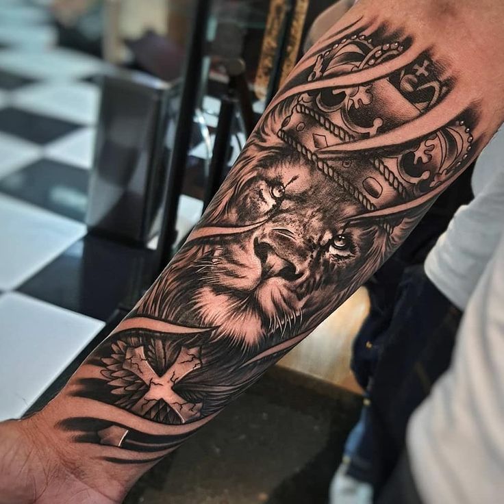 a man's arm with a lion and cross tattoo on the left side of his arm