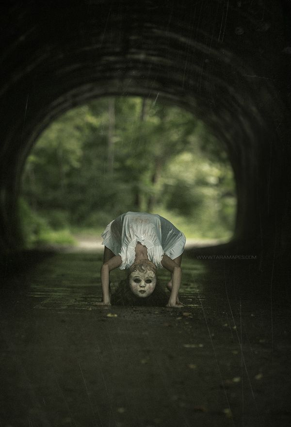 a person is upside down on their head in the middle of a dark tunnel with trees