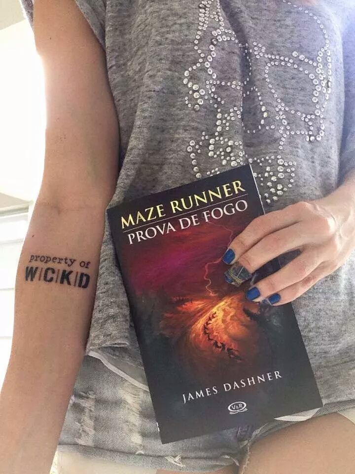 a woman holding a book with tattoos on her arm