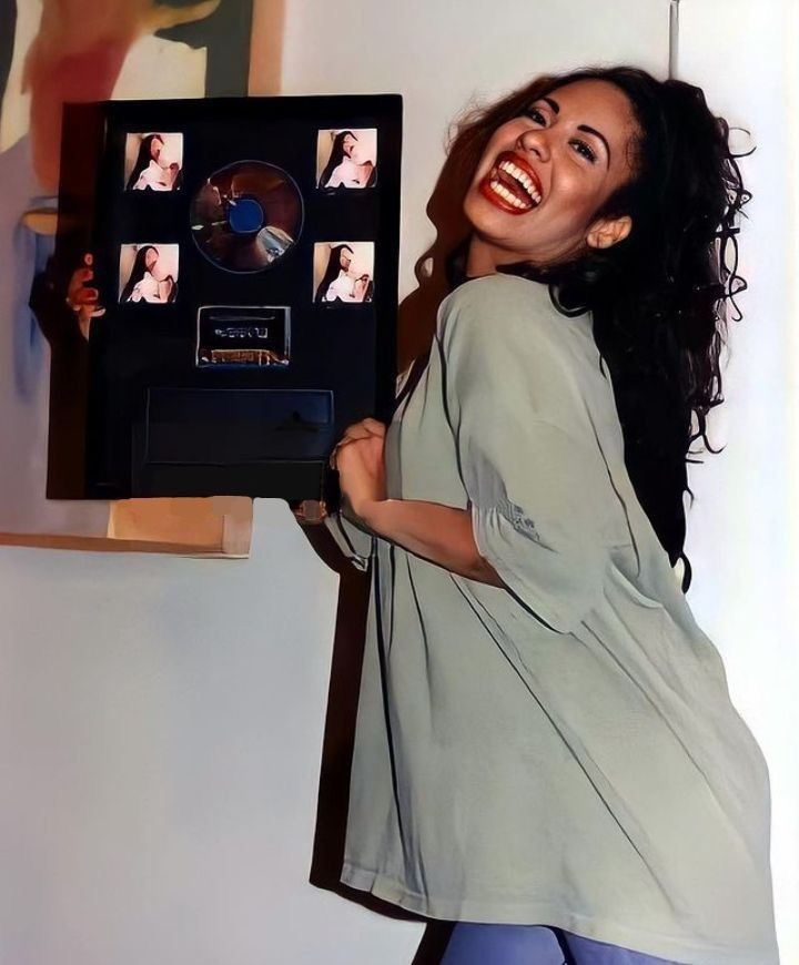 a woman holding up a record in front of her face and smiling at the camera