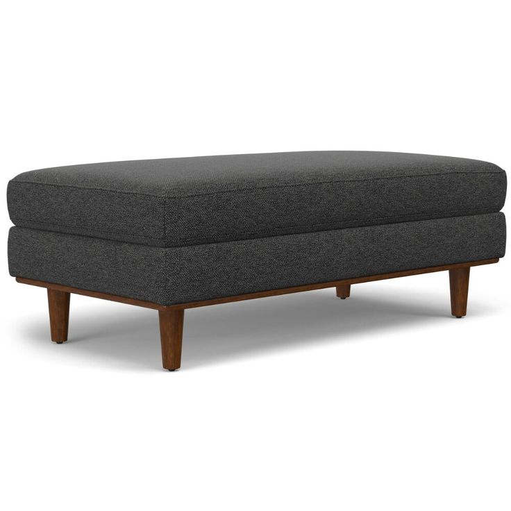 a grey ottoman with wooden legs on a white background